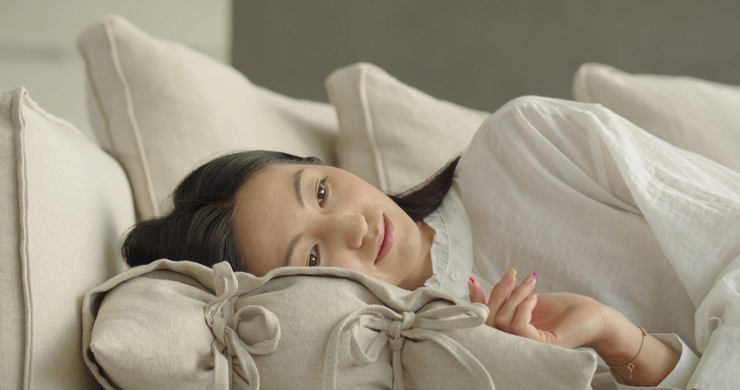 Everyday Japandi Lifestyle - A Tired Woman Puts a Pillow on a Couch and Lies Down 052 Tired Woman Puts a Pillow on a Couch and Lies Down